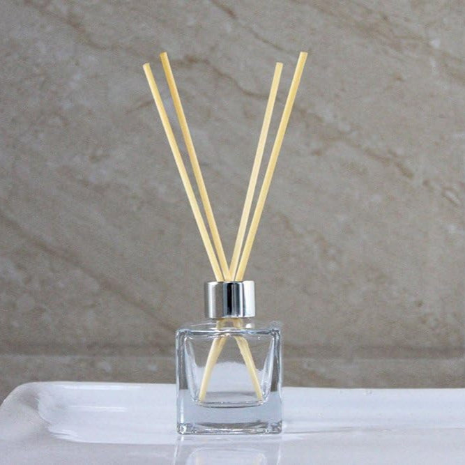 Clear diffuser bottle with wooden sticks on a marble surface