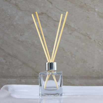 Clear diffuser bottle with wooden sticks on a marble surface