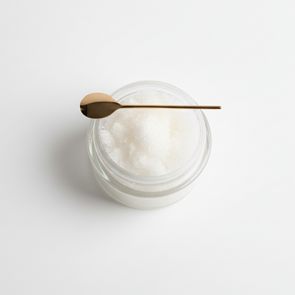 Jar of sugar lip scrub with a spoon on a light gray background